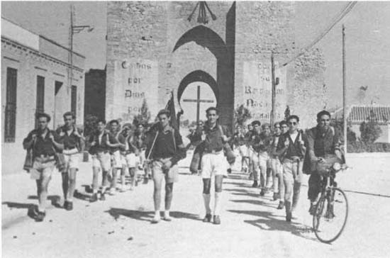Una centuria del Frente de Juventudes con la Puerta de Toledo al fondo en el Ciudad Real de posguerra