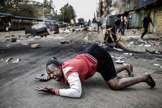 A woman reacts as she passes Kenyan police troops during a protest by supporters of the National Super Alliance (NASA) presidential candidate on August 11th, 2017 at the Mathare slum of Nairobi, a stronghold of Kenyan opposition leader.