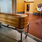 ataud_junto_varias_coronas_flores_funebres_tanatorio_crematorio_memora