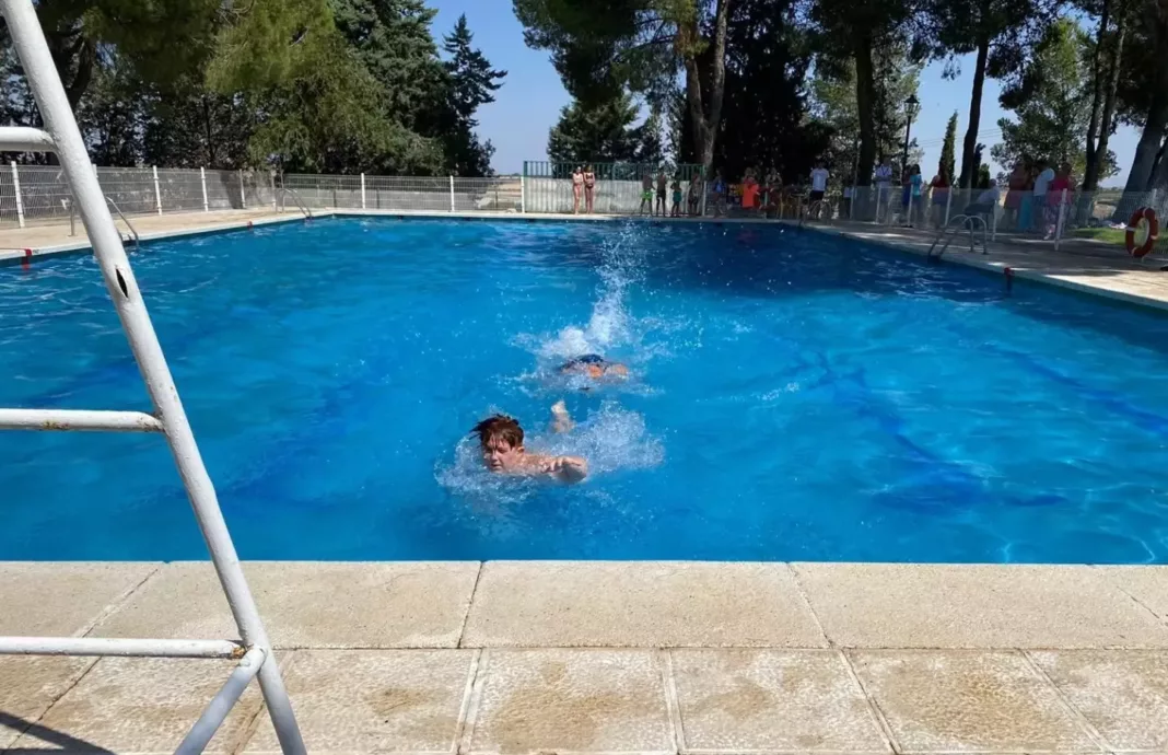 Unos jóvenes nadan en la piscina municipal