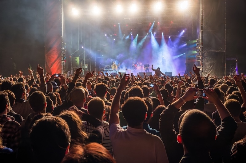 Crowd enjoying a night-time rock concert under vibrant stage lights.